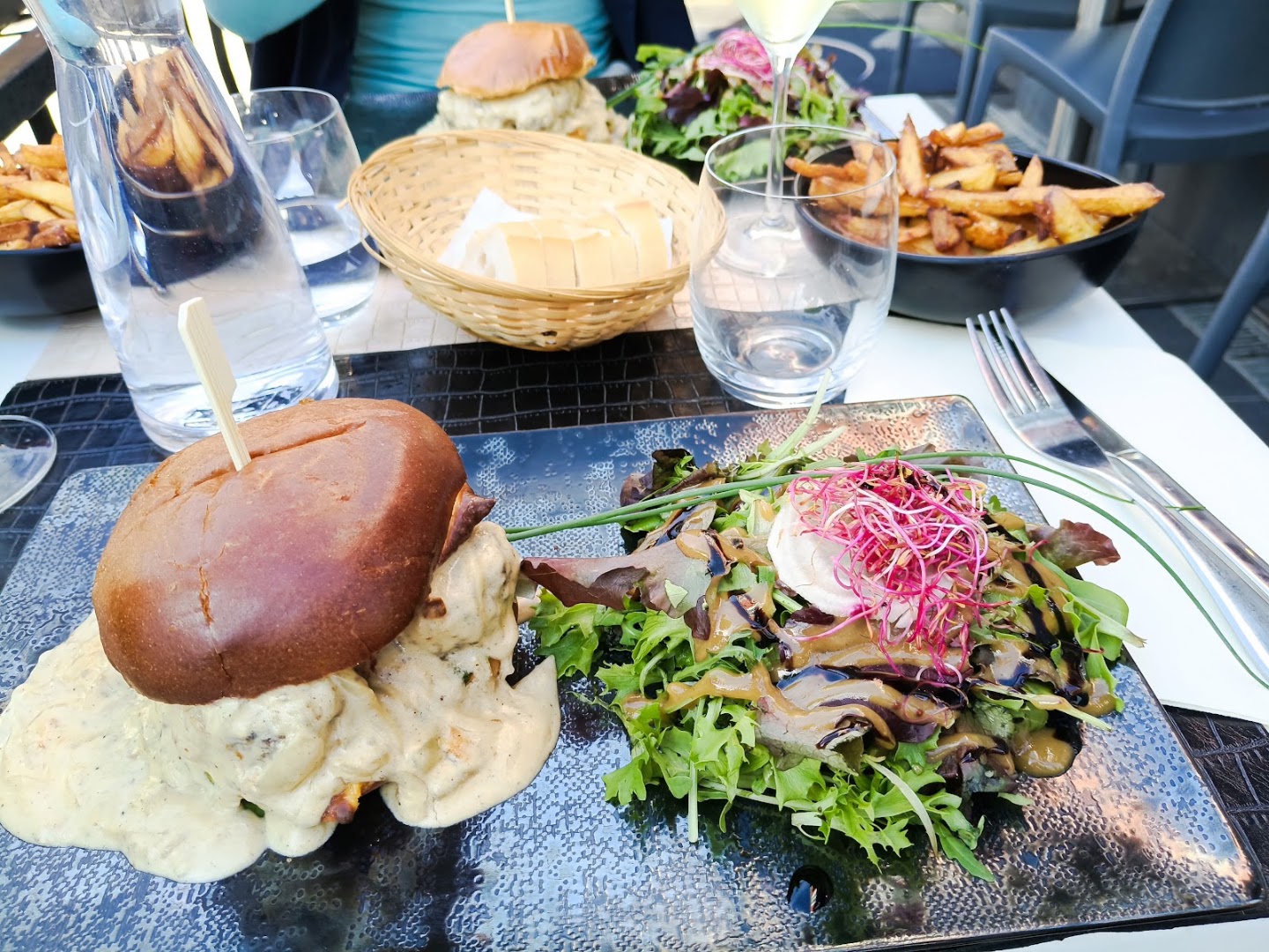 Un burger et ses accompagnements sur une table dressée